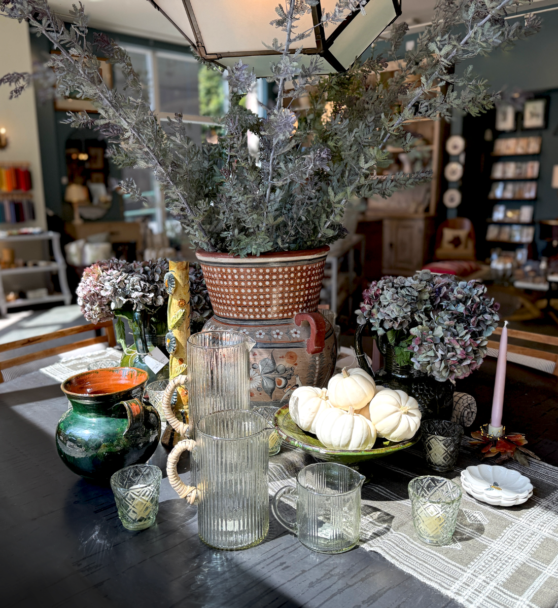 Interior view of Maude Woods in Pasadena featuring vintage glassware, ceramics, and fall décor arranged on a dining table near the shop entrance.