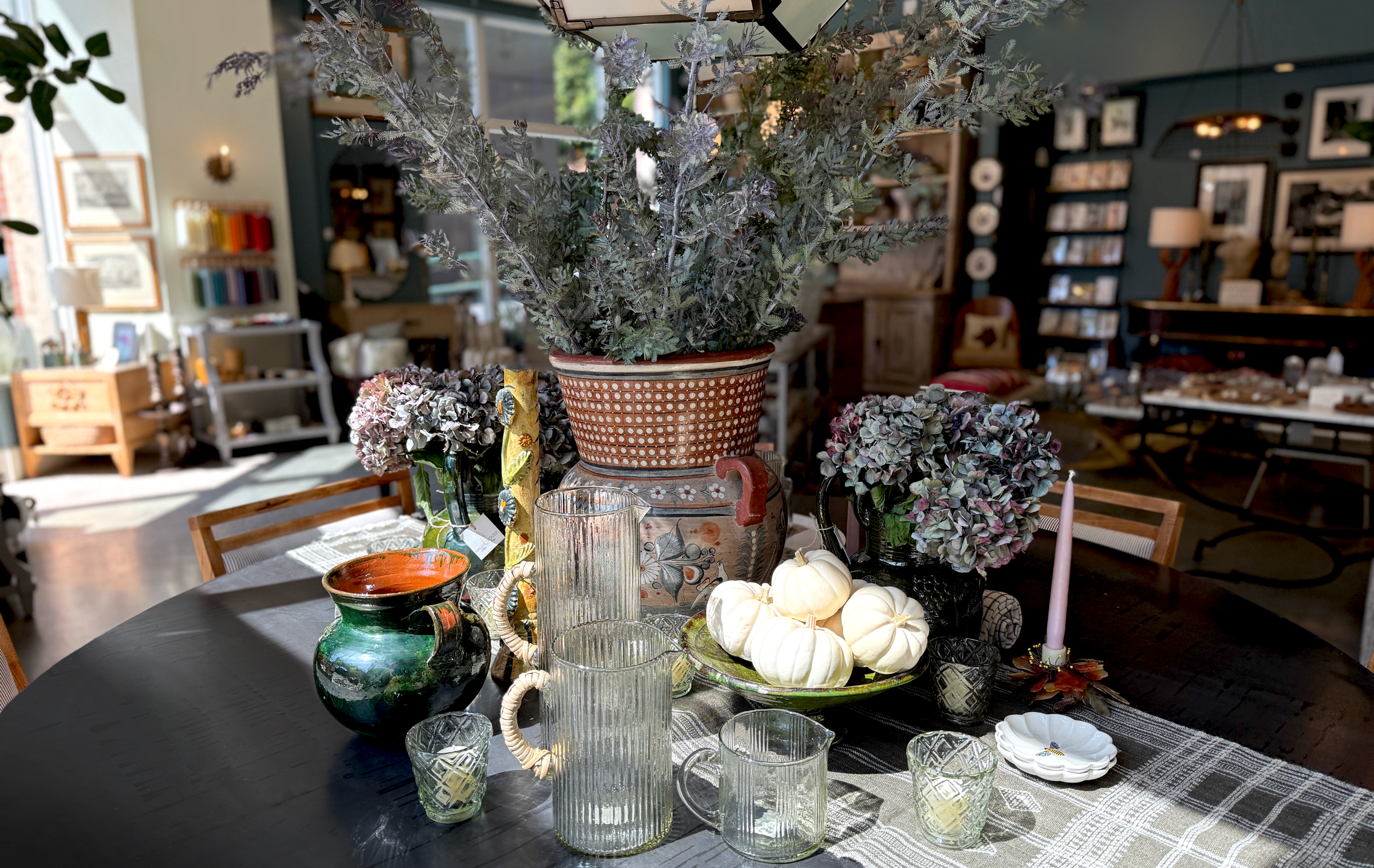 Interior view of Maude Woods in Pasadena featuring vintage glassware, ceramics, and fall décor arranged on a dining table near the shop entrance.