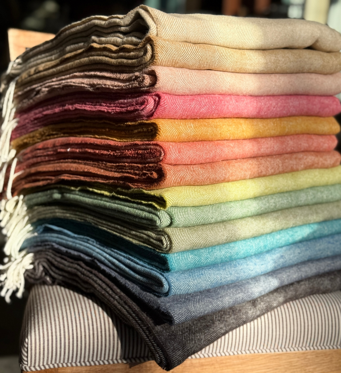Display of cozy throws and blankets at Maude Woods Pasadena, featuring artisanal weaves, vintage textiles, and soft layered textures.
